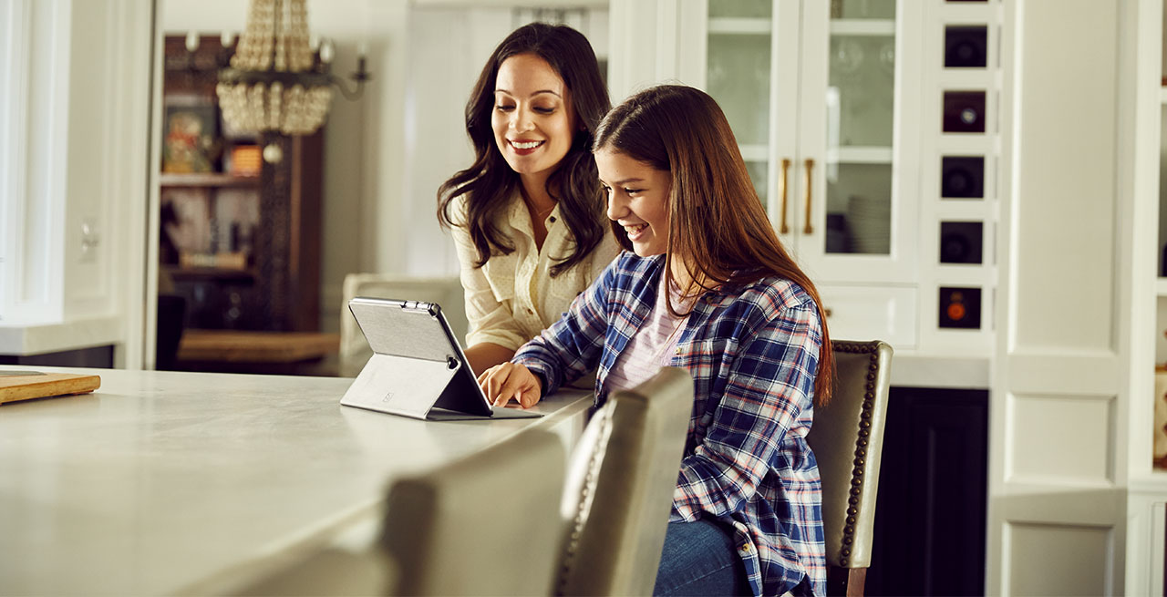 Mom and daughter use tablet at kitchen counter