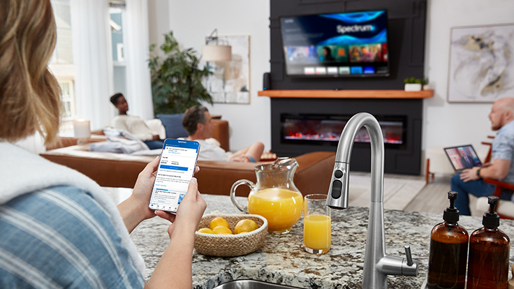 Female using her smartphone in her home, in her kitchen