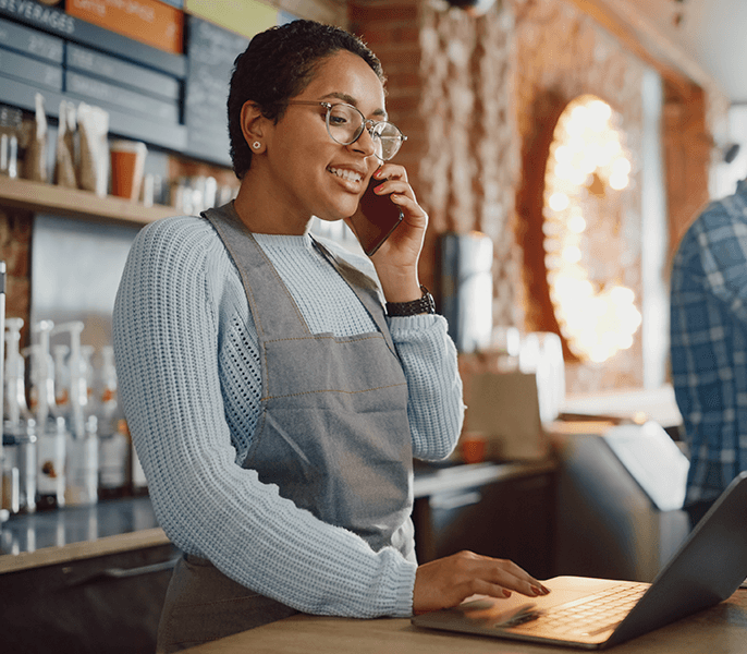 Female Latina small business owner talking on her cell phone in her coffee shop