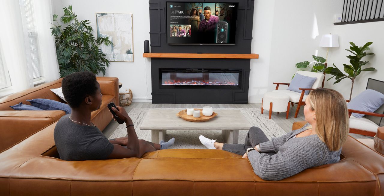 Family watching Xumo programming on their couch, viewed from behind