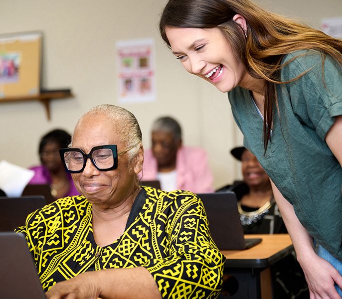  Senior woman getting instruction in a computer lab from a younger female instructor 