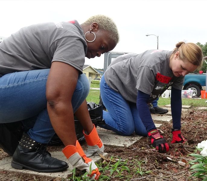 Two women planting flowers at a residential home being repaired